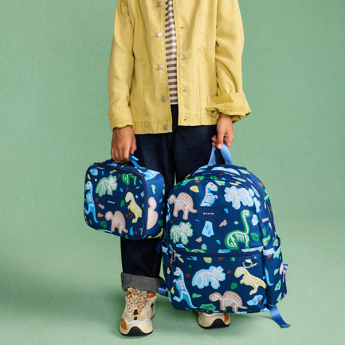 boy holding kane backpack dino fossils and rodgers lunch box dino fossils