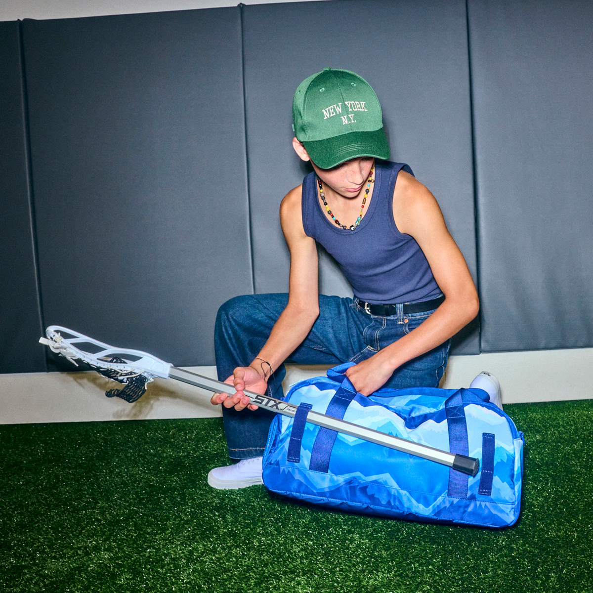 boy putting lacrosse stick in STATE Bags Fenway Sports Duffle Mountains