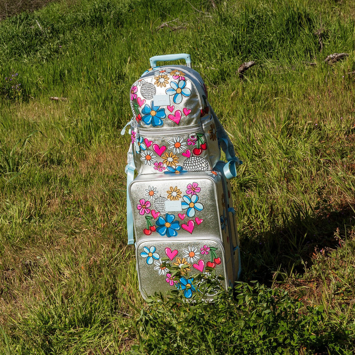 Girl wearing STATE Bags Kane Backpack and Logan Suitcase Metallic Graffiti 