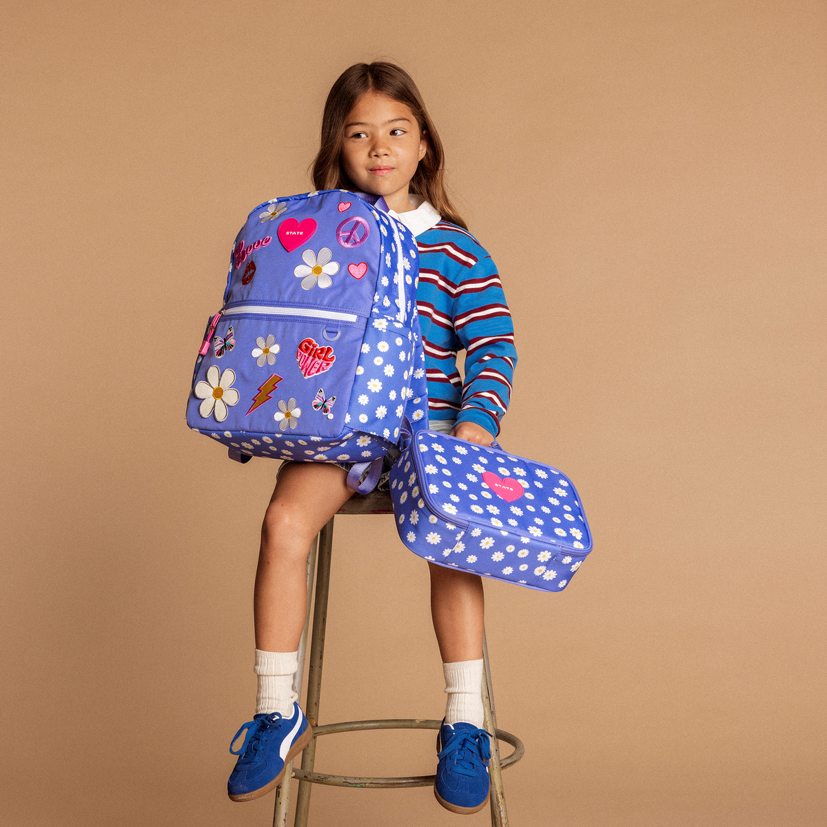 Girl holding state bags kane backpack and rodgers lunch box in girl power
