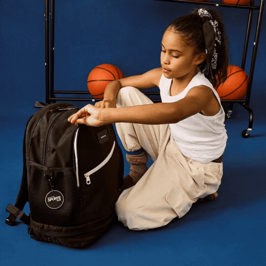 girl putting ball into STATE Bags Ozzie Ball Bag 