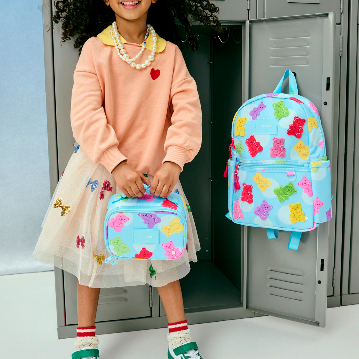 girl holding STATE Bags Kane Mini Backpack and Mini Rodgers Gummy Bears