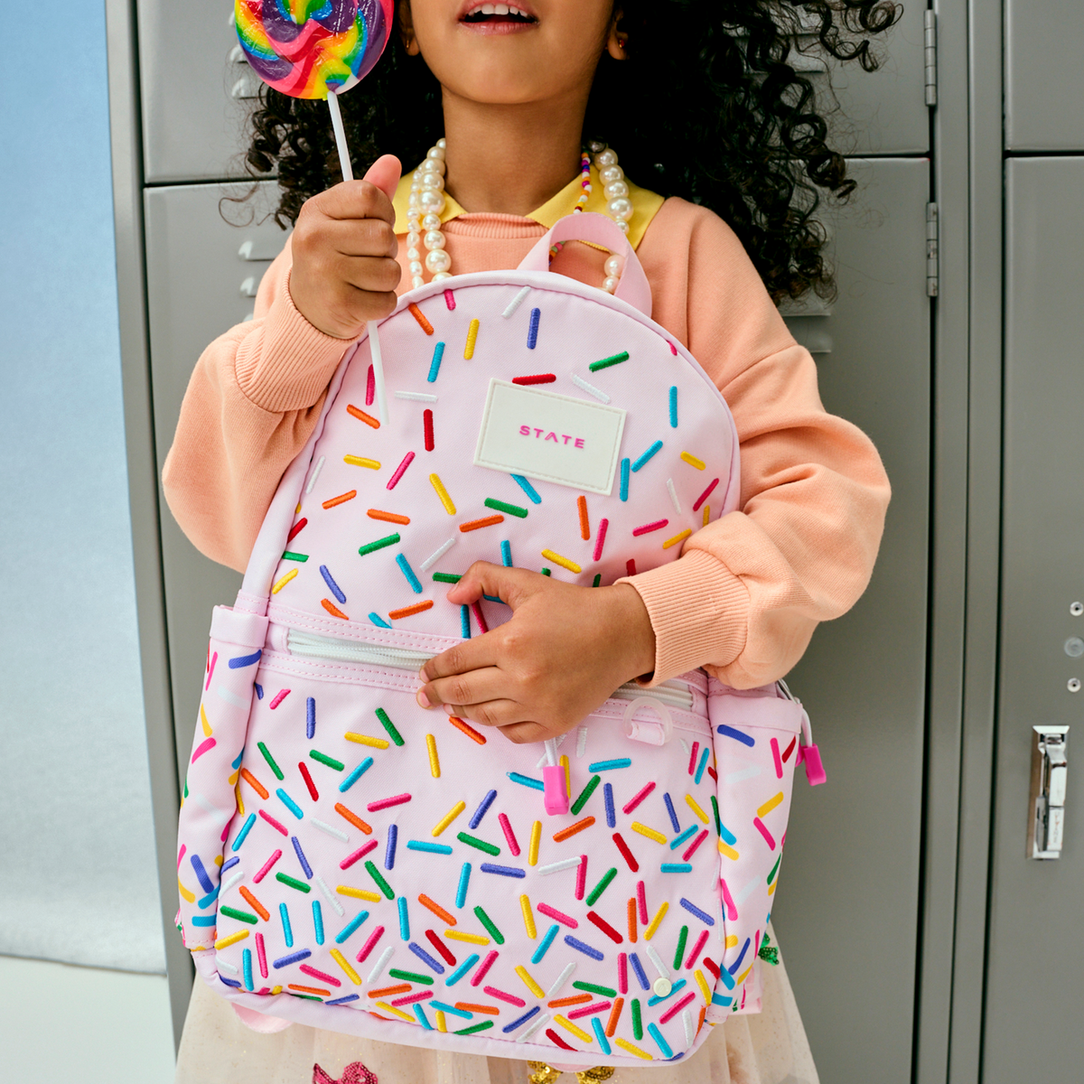 girl holding with STATE Bags kane mini backpack sprinkles
