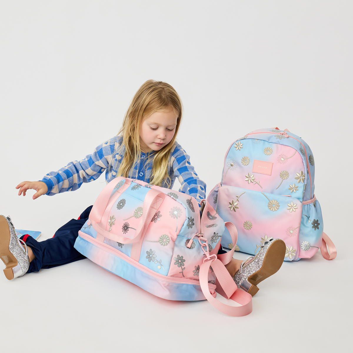 girl sitting with Wren Weekender and Kane Backpack Dreamy FLoral